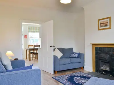 a living room with two blue chairs and a fireplace at 14 Greta Villas in Keswick