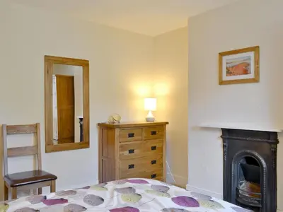 a bedroom with a bed and a dresser and a fireplace at 14 Greta Villas in Keswick