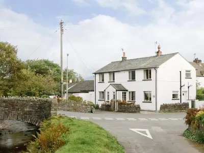 a white house on the side of a road at Bridge Cottage in Braithwaite