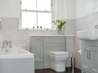 a white bathroom with a toilet and a sink at Poachers Cottage in Keswick