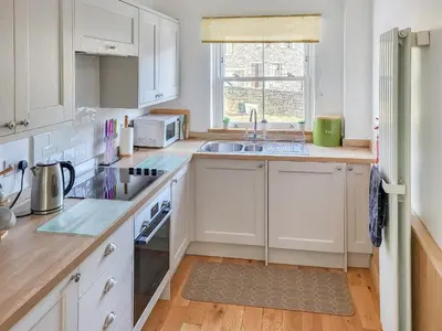 a kitchen with white cabinets and a sink at Poachers Cottage in Keswick