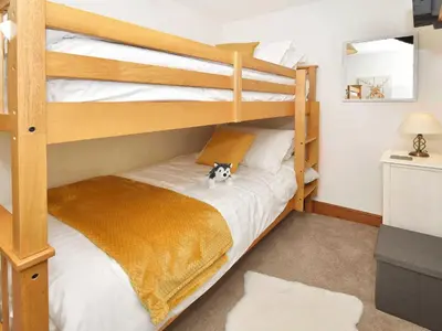 a bedroom with bunk beds with a dog sitting on the bed at Osprey Cottage in Bassenthwaite