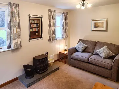 a living room with a couch and a stove at Joan's Cottage in Braithwaite