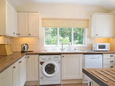 a kitchen with a washing machine and a sink at Joan's Cottage in Braithwaite