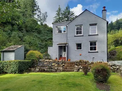 a gray house with a stone wall in the yard at Oak Lea in Braithwaite