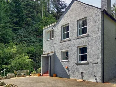 a gray brick house with a door and windows at Oak Lea in Braithwaite