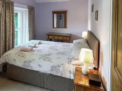 a bedroom with a bed and a table with two lamps at Oak Lea in Braithwaite