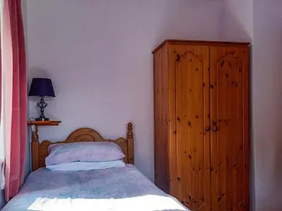 a bedroom with a bed and a wooden cabinet at Oak Lea in Braithwaite