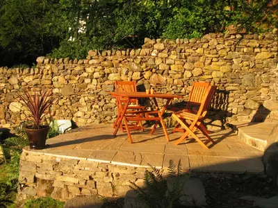 two chairs and a table in front of a stone wall at The Larches in Braithwaite