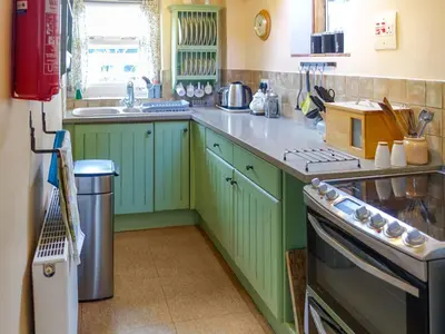 a kitchen with green cabinets and a sink at Thwaite Hill Cottage in Braithwaite
