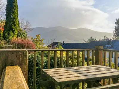 a wooden bench on a wooden fence with mountains in the background at Thwaite Hill Cottage in Braithwaite