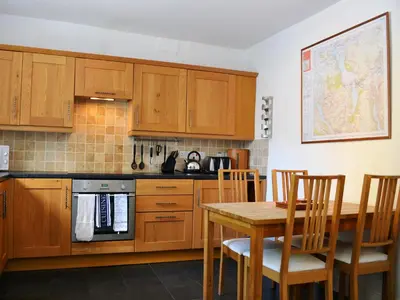 a kitchen with wooden cabinets and a table with chairs at Croft Cottage in Braithwaite