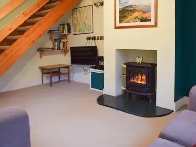 a living room with a stove and a staircase at Beech End in Braithwaite