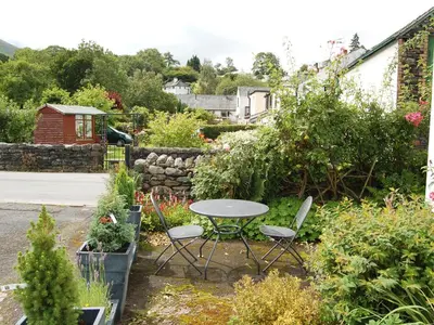 a table and chairs in a garden with plants at Beech End in Braithwaite