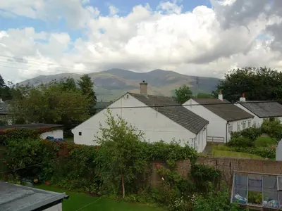 a group of white houses with mountains in the background at Beech End in Braithwaite