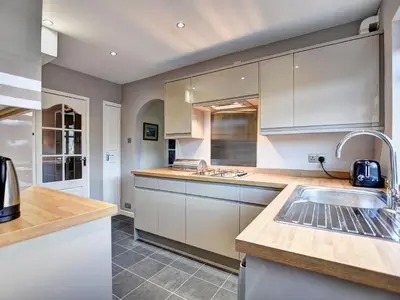 a kitchen with white cabinets and a sink at Roseworth in Portinscale