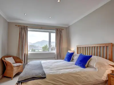 a bedroom with a bed with blue pillows and a window at Roseworth in Portinscale