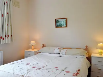 a bedroom with a bed with white sheets and two lamps at Whitegates in Portinscale