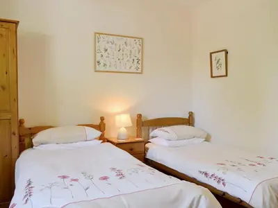 two twin beds in a room with white walls at Whitegates in Portinscale