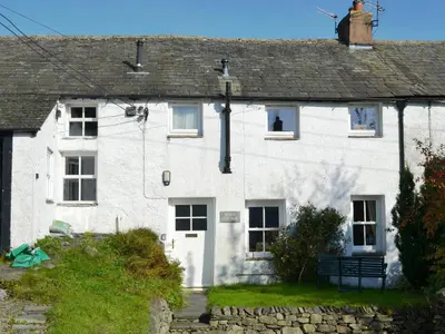 a white house with a bench in front of it at Blease Cottage in Threlkeld
