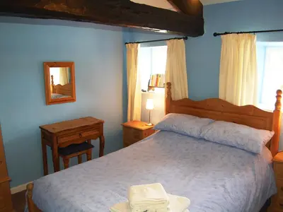 a bedroom with a bed and a table and a mirror at Blease Cottage in Threlkeld