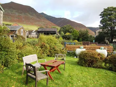 a picnic table and chairs in a yard with mountains at Foxhole in Threlkeld