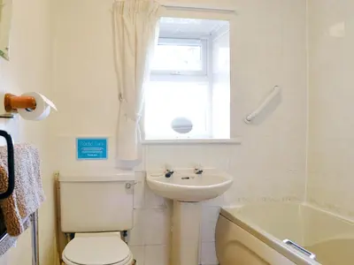 a bathroom with a toilet and a sink and a window at Bridge House in Threlkeld