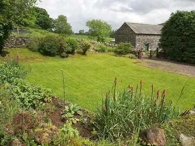 a garden with a stone house and a yard at Lookin How in Dockray