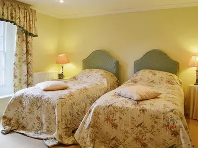 two beds sitting next to each other in a bedroom at Laundry Cottage in Uldale