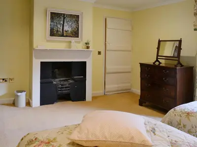 a bedroom with a fireplace and a bed and a dresser at Laundry Cottage in Uldale