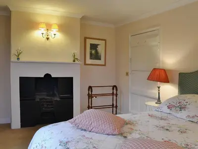 a bedroom with a bed and a fireplace at Laundry Cottage in Uldale