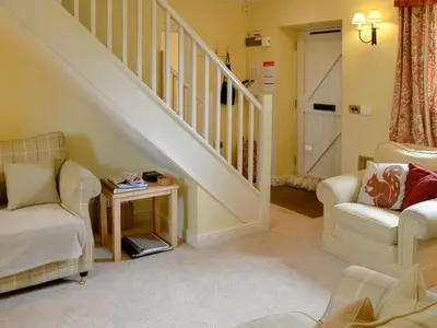 a living room with two chairs and a staircase at The Old Stables in Uldale