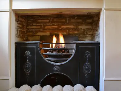 a black fireplace with flames in it at The Old Stables in Uldale