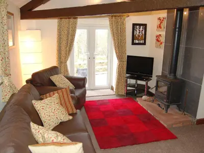 a living room with a couch and a wood stove at Nuthatch Cottage in Westward