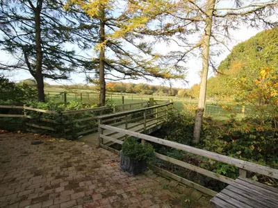 a wooden bench next to a fence and a field at Nuthatch Cottage in Westward