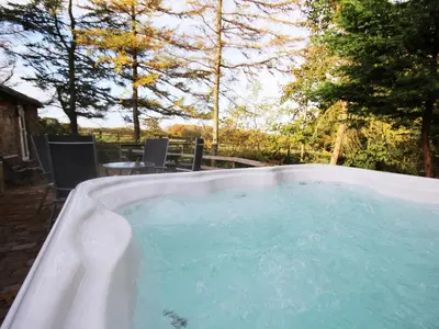 a hot tub with blue water in a backyard at Nuthatch Cottage in Westward