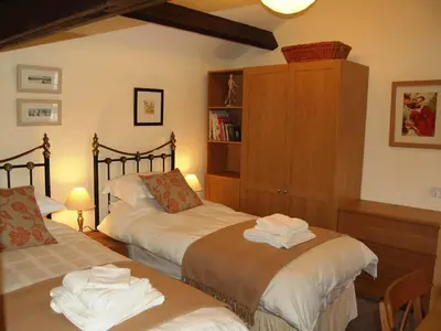 a bedroom with two beds and a book shelf at Nuthatch Cottage in Westward