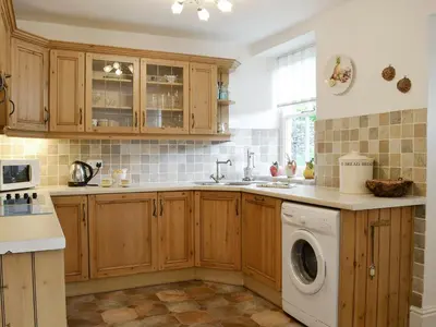 a kitchen with wooden cabinets and a washing machine at Roundhill Cottages 1 in Grasmere