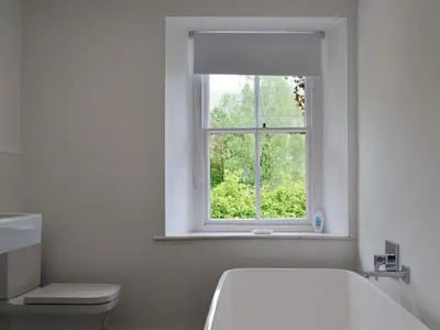 a white bathroom with a toilet and a window at Roundhill Cottages 1 in Grasmere