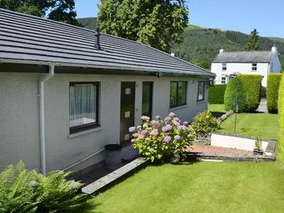 a small house with a yard with flowers in front of it at Fourwinds in Keswick