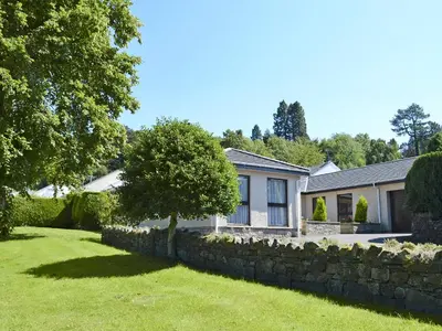a house with a stone wall and a yard at Fourwinds in Keswick