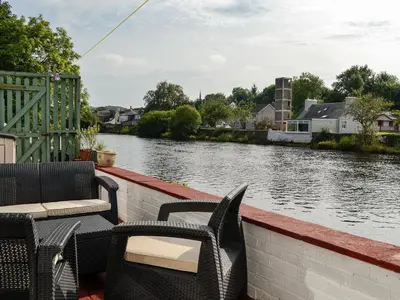 a boat with chairs and tables on a river at Minnow Cottage in Newton Stewart