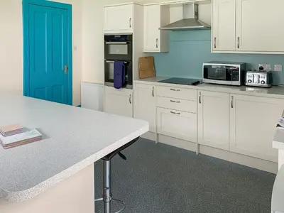 a kitchen with white cabinets and a blue door at Bonshawside Farmhouse in Kirtlebridge
