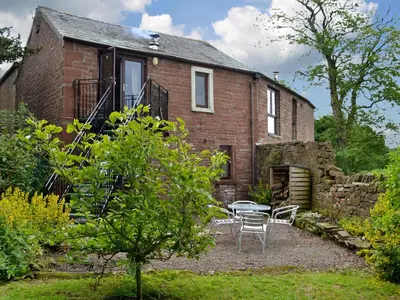 a brick house with a table and chairs in front of it at Grooms Cottage in Plumbland
