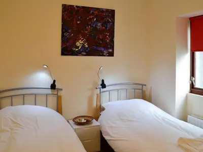 two beds in a bedroom with a painting on the wall at Grooms Cottage in Plumbland