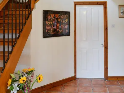 a hallway with a white door and a vase of flowers at Grooms Cottage in Plumbland