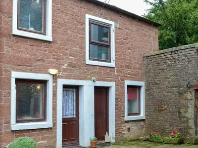 a brick house with white windows and a brick wall at Grooms Cottage in Plumbland