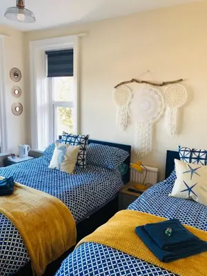 two beds in a room with blue and yellow at Lismore Guest House in Whitehaven