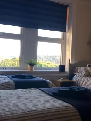 a bedroom with two beds and a large window at Lismore Guest House in Whitehaven