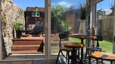 a patio with a table and stools in front of a door at Ayrshire Holiday Cottage in Girvan